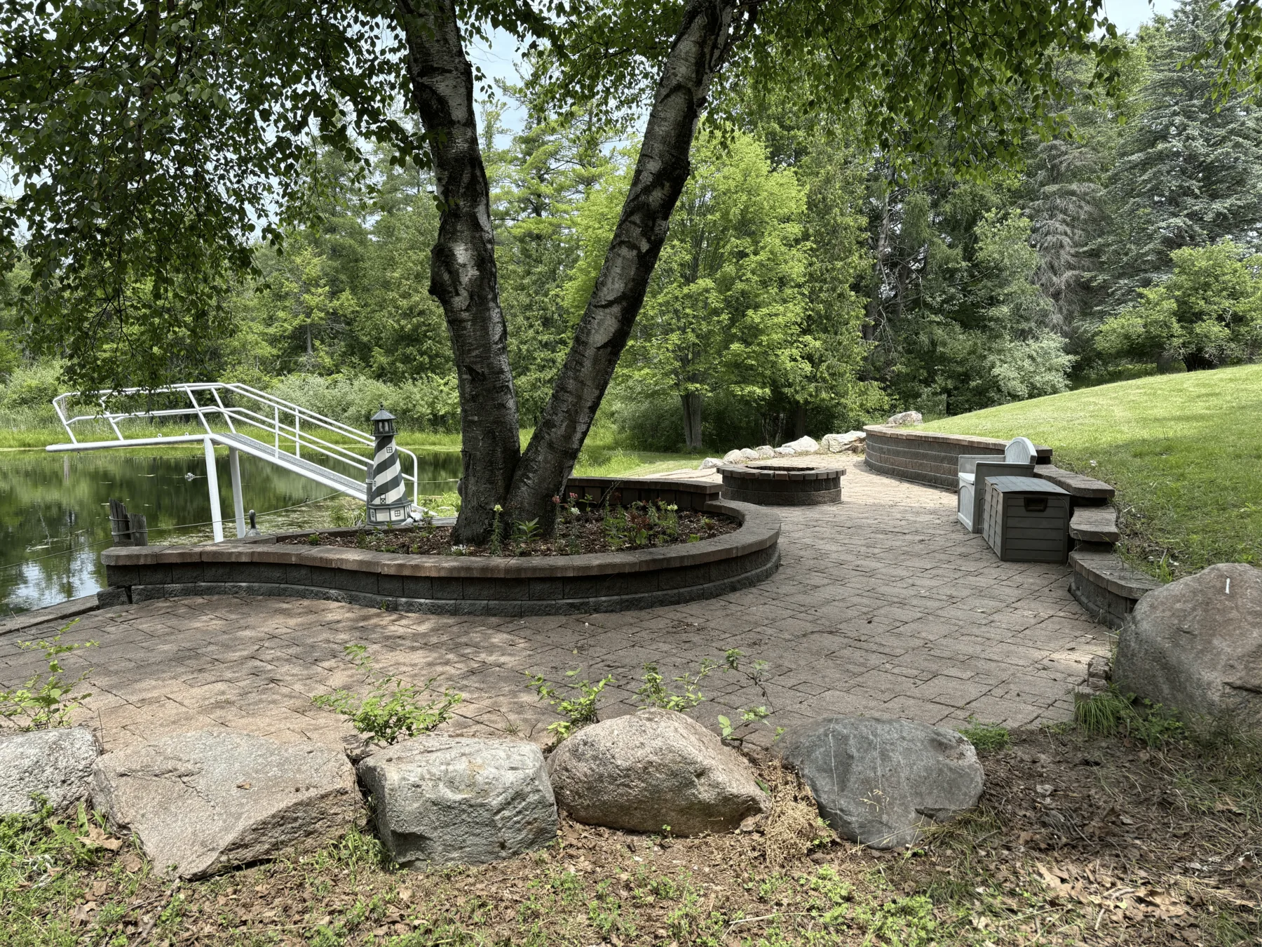 Landscaped patio and firepit beneath a mature tree