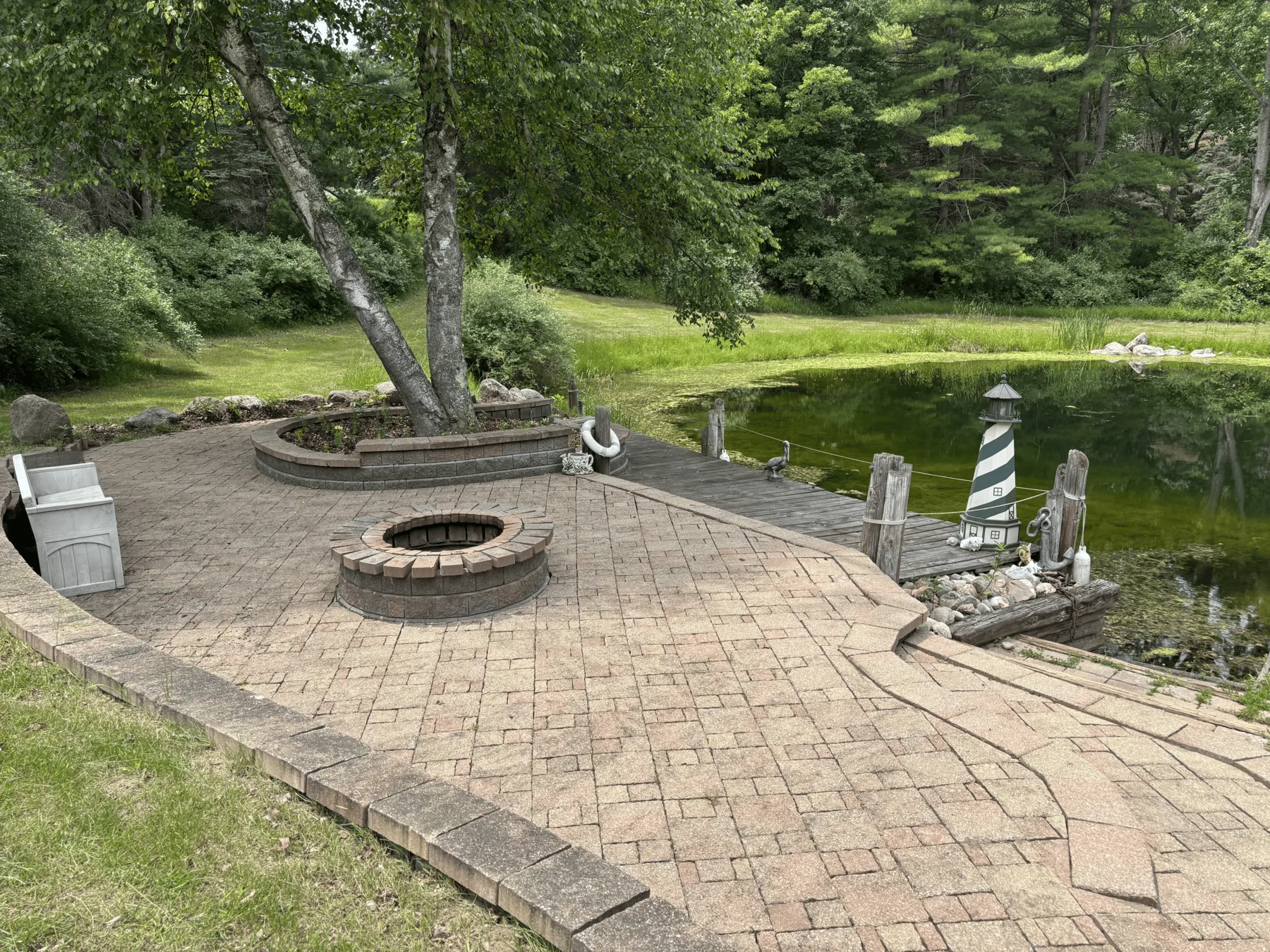 Paver patio, firepit and lawn beside the pond