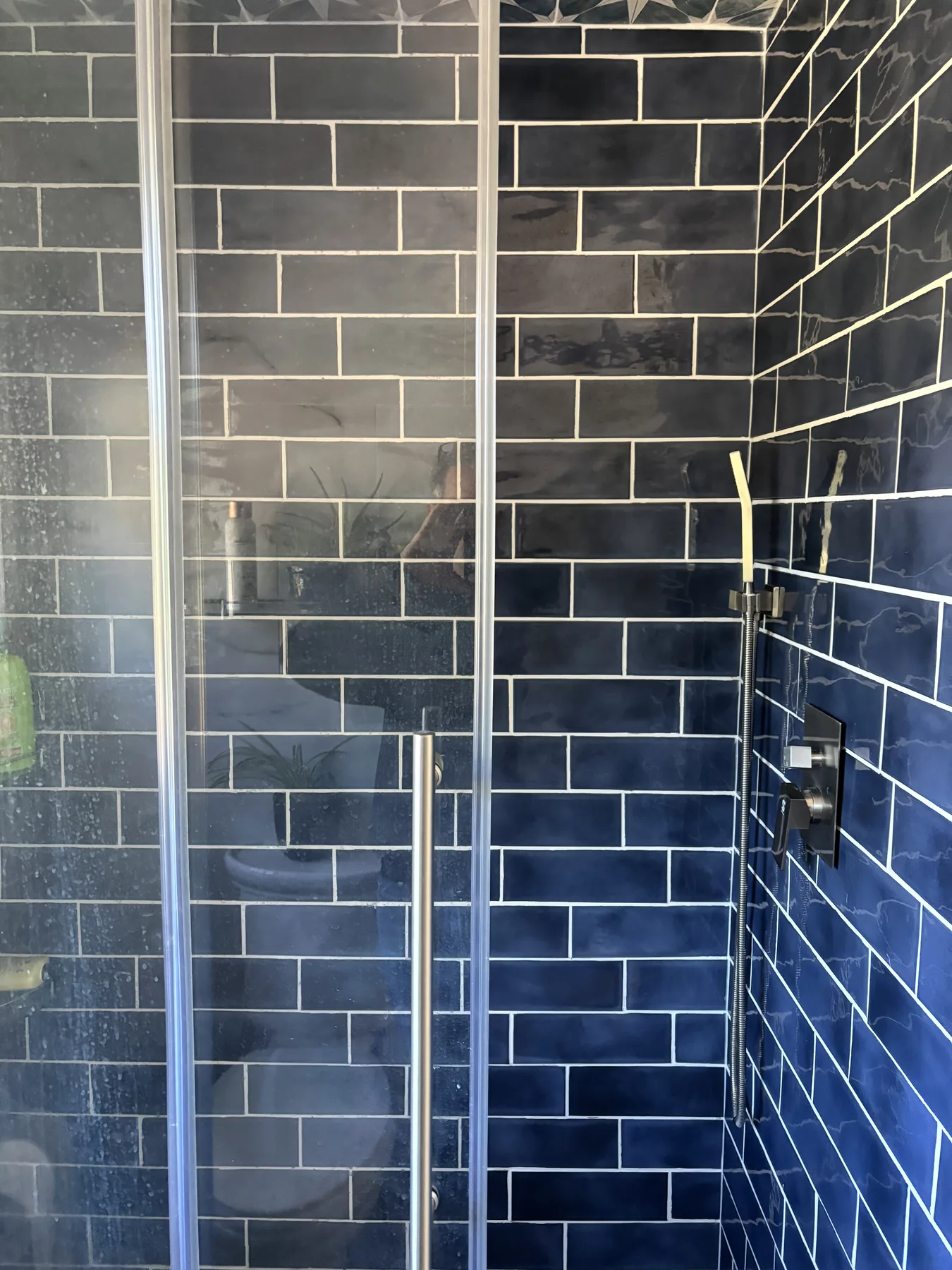Dark tiled shower with glass enclosure and black fixtures